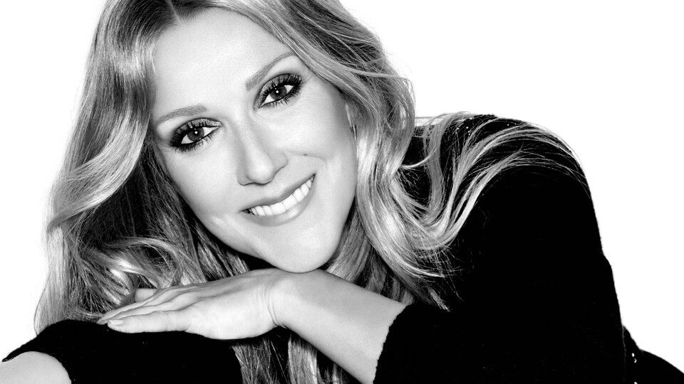 Portrait en noir et blanc de Céline Dion, qui sourit.