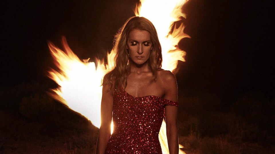 Couverture de l'album « Courage », qui représente Céline Dion, en robe longue rouge, devant un feu.
