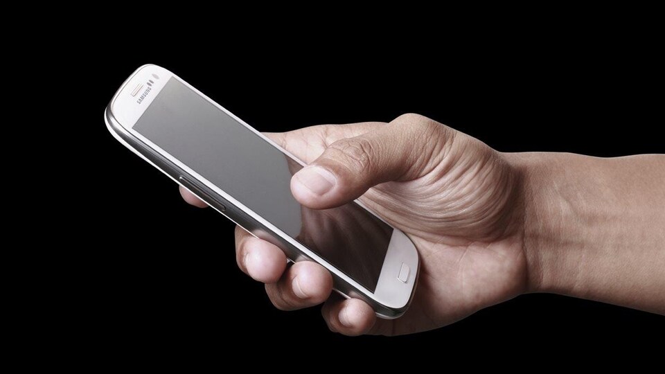 Un homme tient un téléphone intelligent.