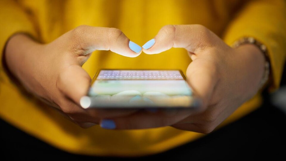 Les mains d'une femme tiennent un téléphone cellulaire.