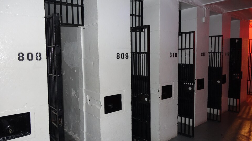 Une rangée de portes de fer noir qui ressortent sur les murs de pierre blancs.