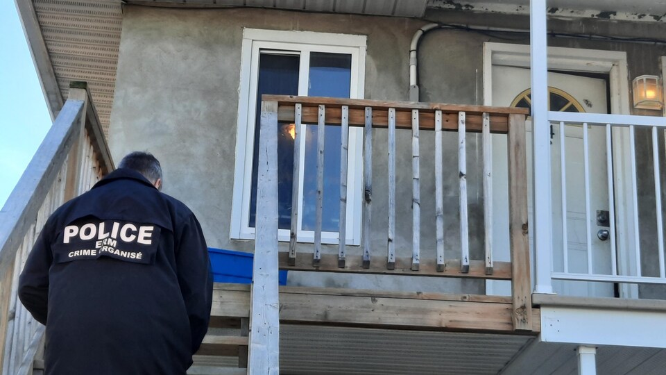 Un policier se dirige vers la porte d'une maison.