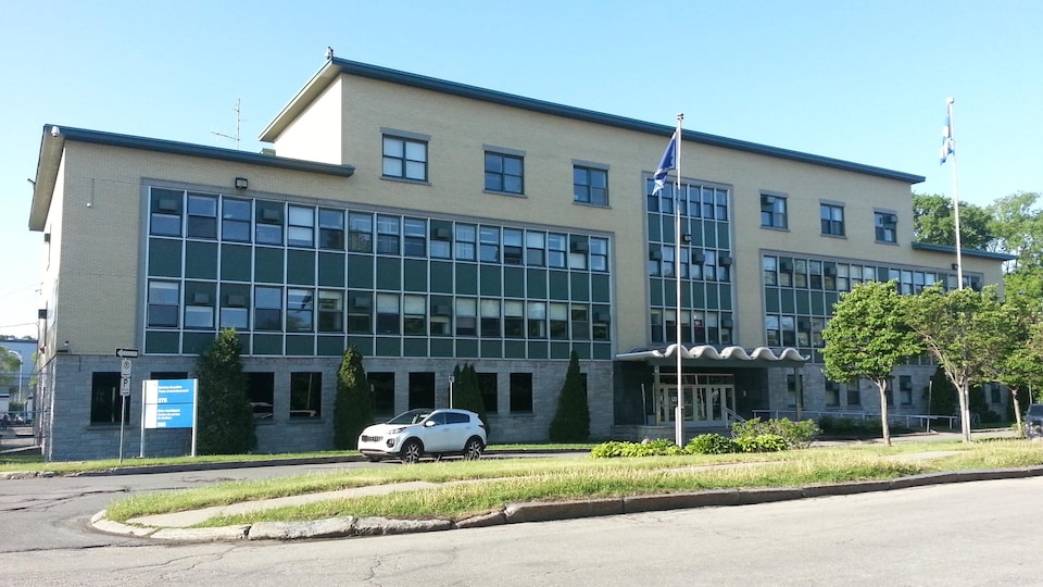 Vue sur la façade du bâtiment abritant la Cour municipale de Québec et le poste de police de l’arrondissement de La Cité-Limoilou. Il s’agit d’une construction en briques jaunes de trois étages.