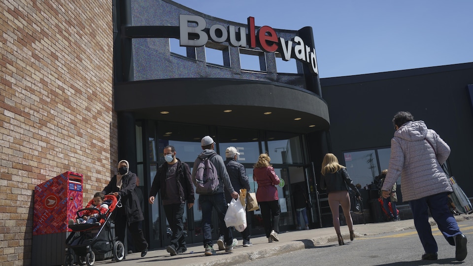 Des gens devant l'entrée principale du centre commercial Le Boulevard.