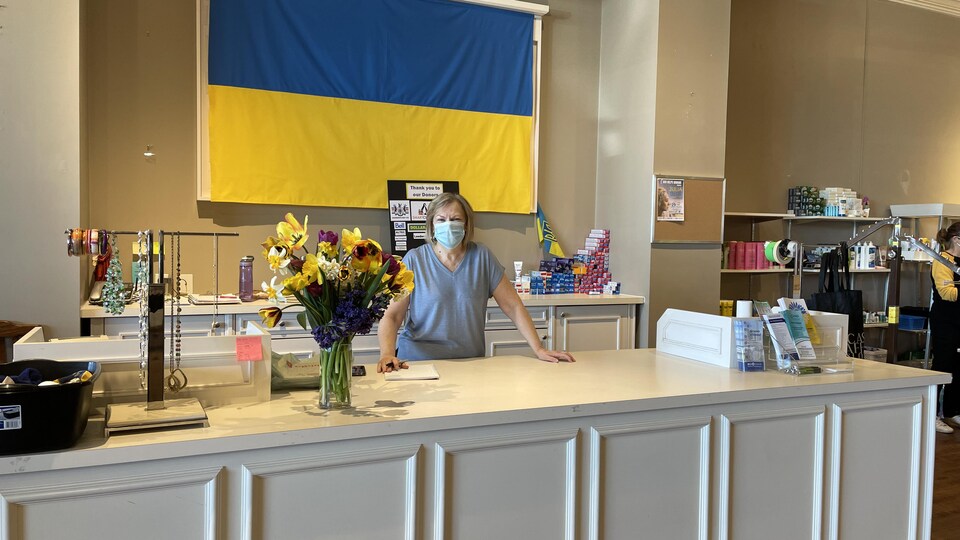 Luba Tarapacky devant un drapeau ukrainien et derrière un comptoir.