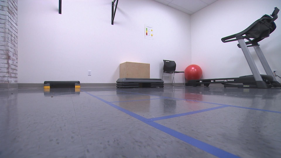 Une salle avec un tapis de course, un ballon et autres objets d'entraînement.