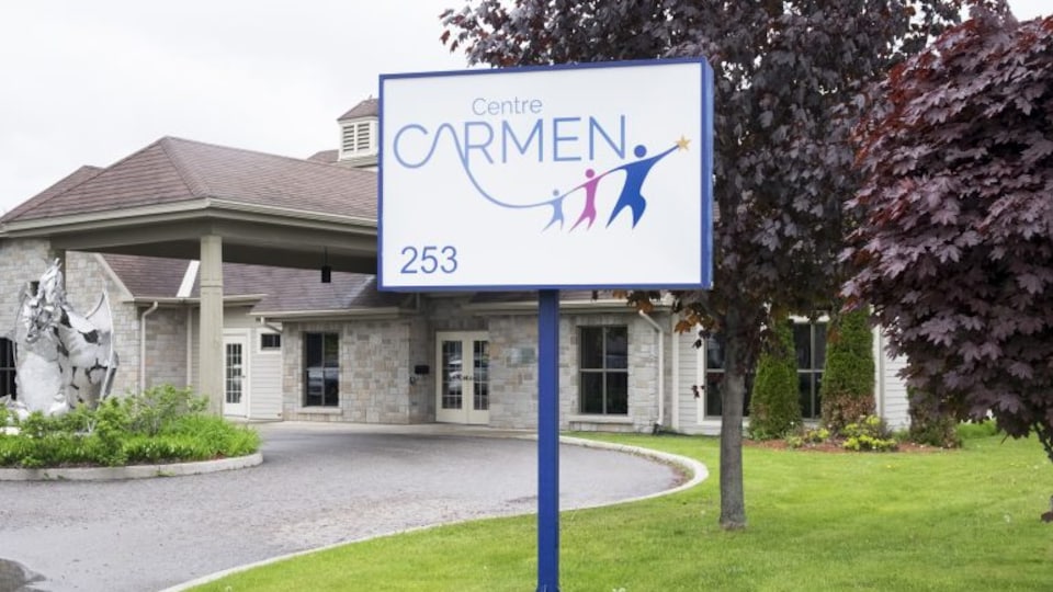 Affiche sur laquelle on peut lire "Centre CARMEN" devant un édifice.