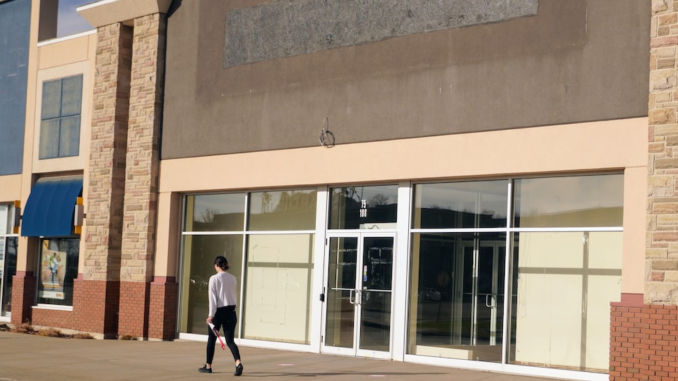 Une femme marche devant un magasin fermé