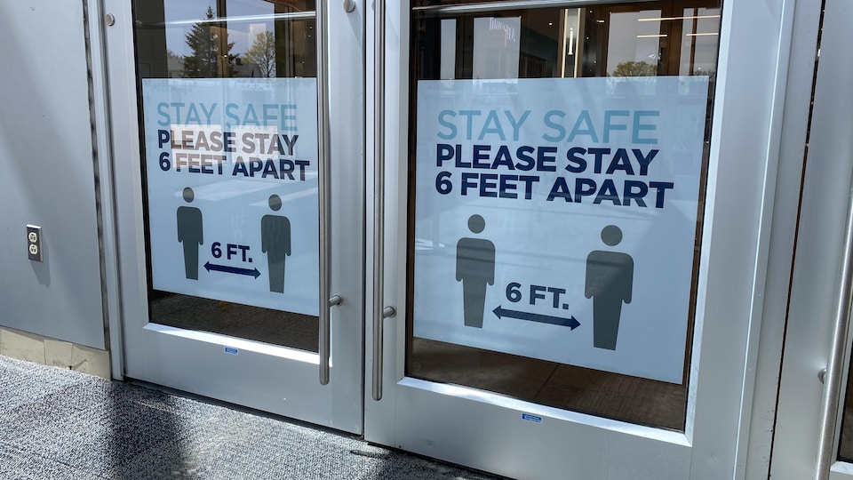 Une affiche à l'entrée d'un centre commercial demande aux clients de se tenir à deux mètres les uns des autres.