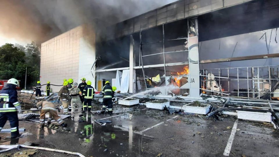 Des pompiers tentent d'éteindre un incendie dans un grand bâtiment. 