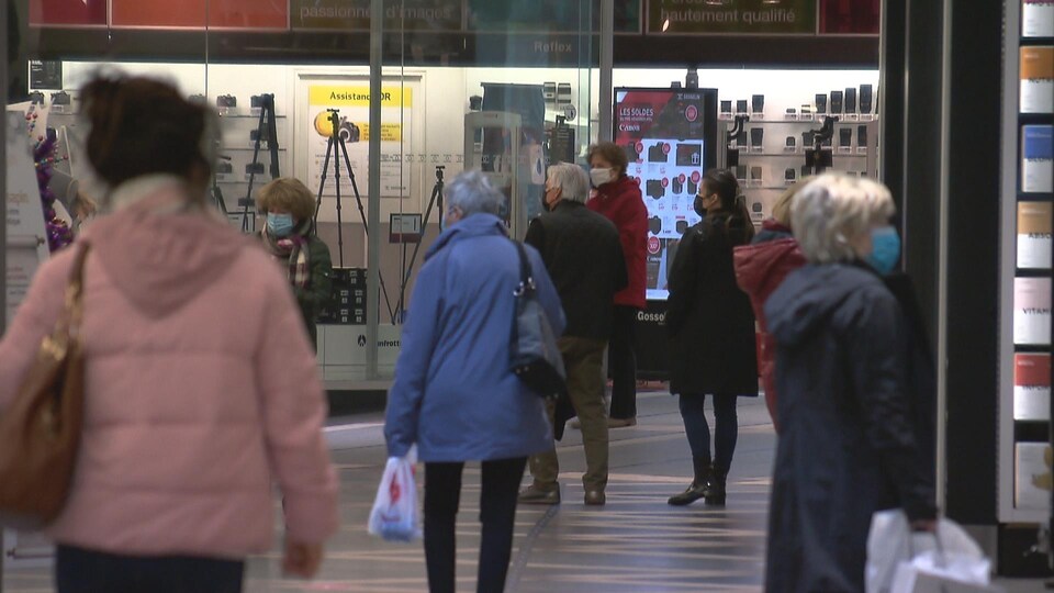Des gens magasinent dans un centre commercial.