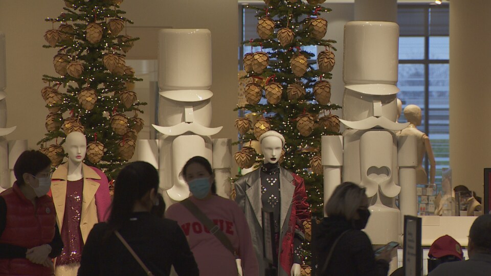 Des clientes devant de géants casse-noisettes et des sapins de Noël dans un centre commercial.