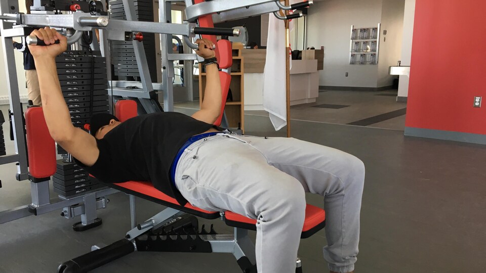 Un jeune homme essaie un appareil de conditionnement physique.