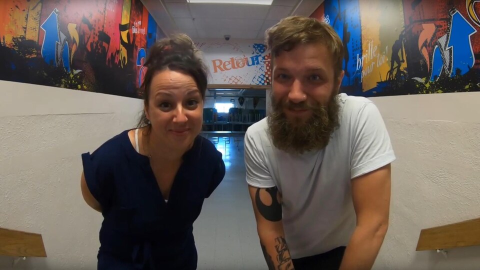 Une femme et un homme sourient à la caméra dans couloir du centre Le Retour.