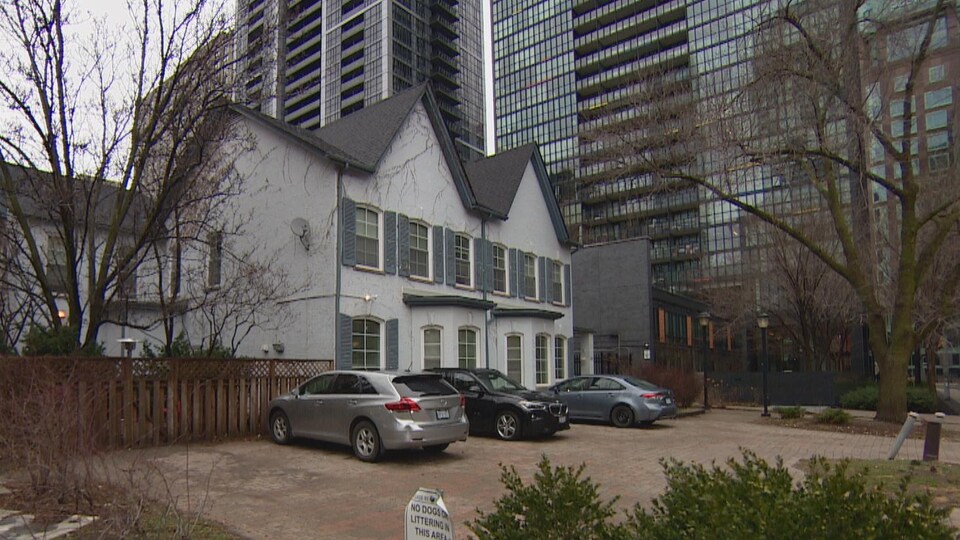 Une maison plutôt ancienne, avec une cour et un stationnement en avant, au centre-ville de Toronto.