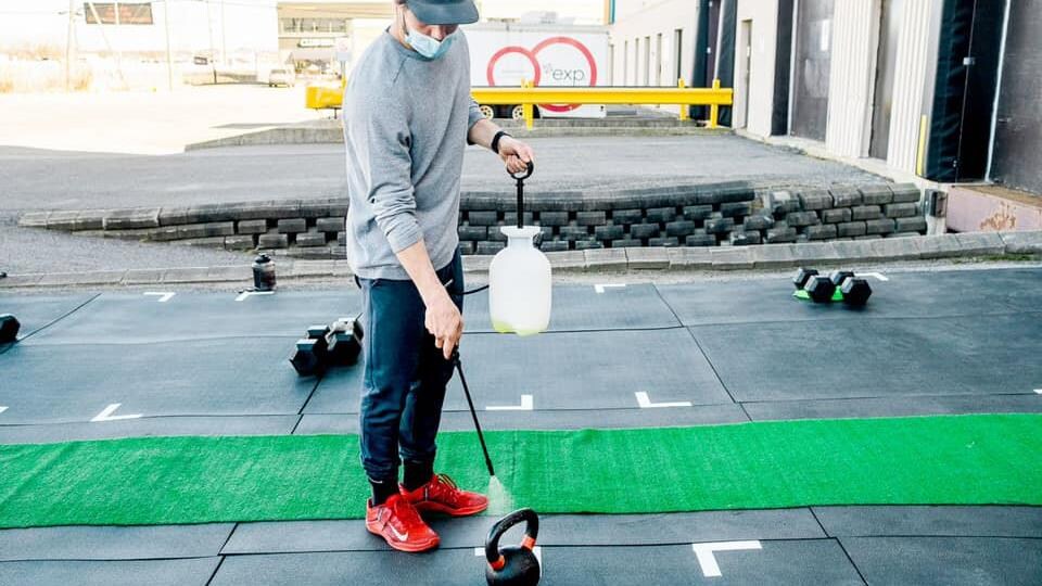 Un employé du centre Hyperactif, à Québec, désinfecte un poids.