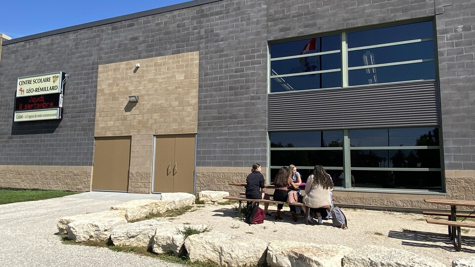Des élèves sont assis sur une table à l'extérieur de l'école. 