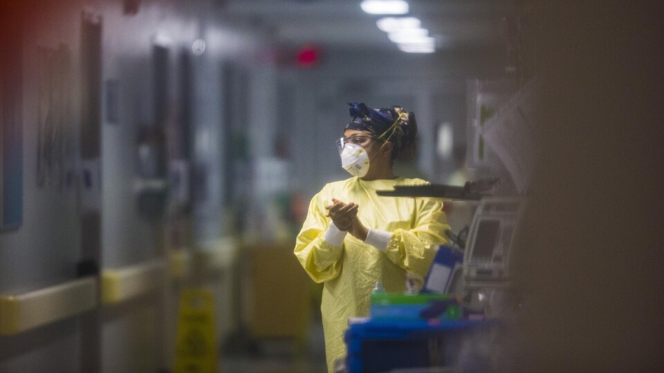 Une infirmière se lave les mains dans un corridor.