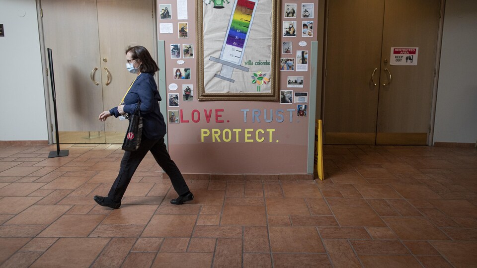 Une infirmière passe devant un panneau qui fait la promotion de la vaccination à la Villa Columbo, à Toronto.