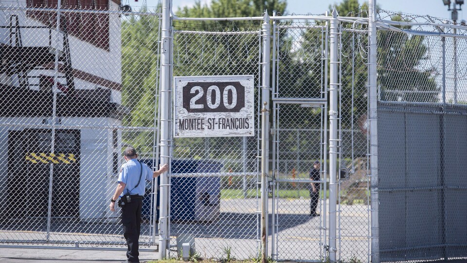 Un garde se tient devant les portes d'un centre de rétention d'immigrants à Laval, au Québec, le lundi 15 août 2016. 