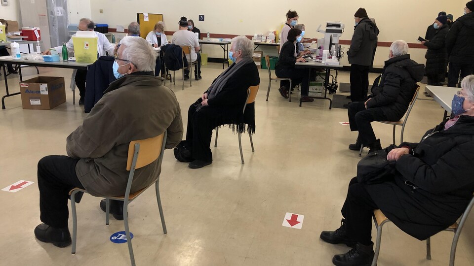 Des personnes attendent, assises sur des chaises.