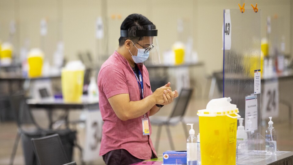 Un travailleur se désinfecte les mains à un centre de vaccination à Toronto.