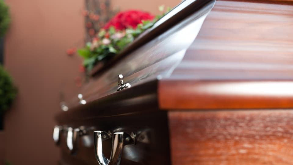 Un cercueil au cours d'une cérémonie funéraire avec des fleurs posées dessus