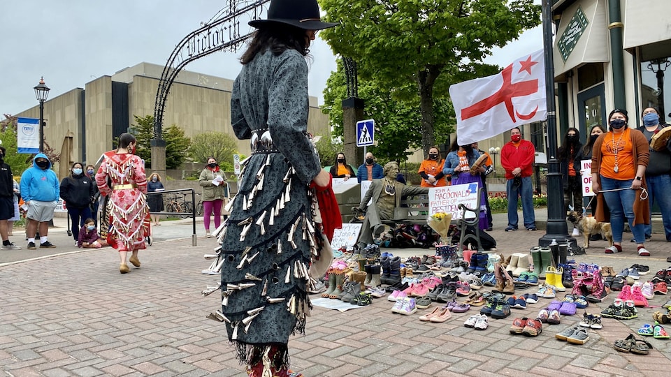 A woman collects herself in front of children's shoes.