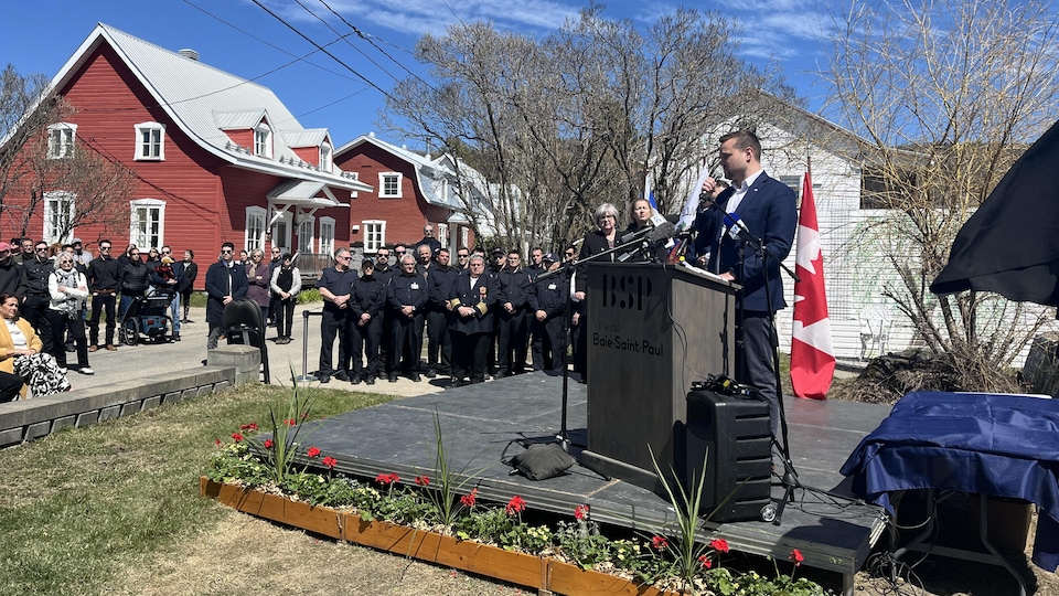 Le maire de Baie-Saint-Paul, Michaël Pilote, parle au microphone lors de la cérémonie de commémoration.