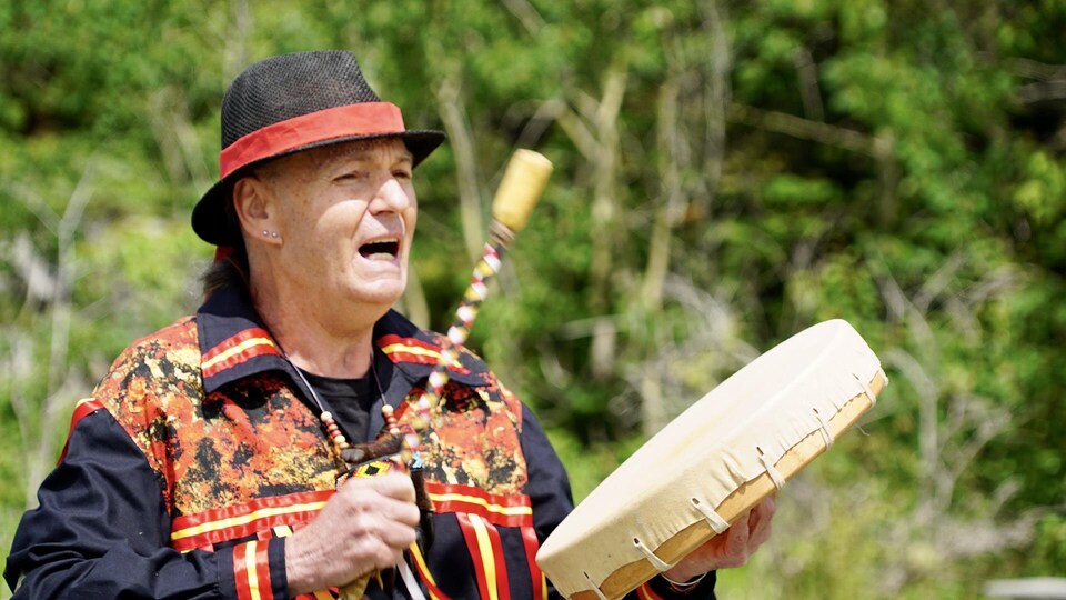 Un homme malécite tape sur un tambour et chante.