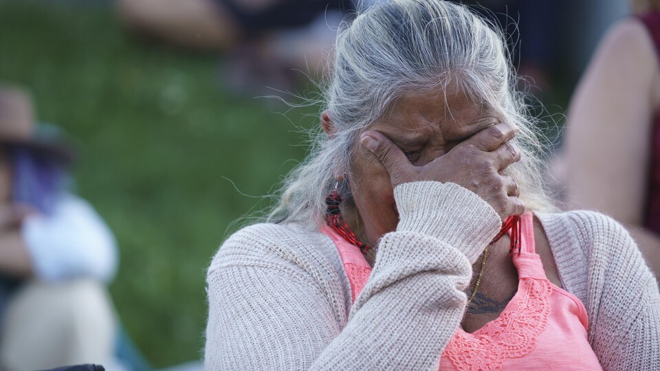 Une femme en pleurs se tient la tête avec sa main droite.