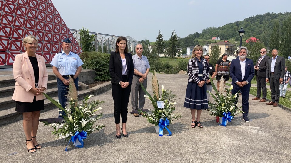 Des dignitaires posent devant des gerbes de fleurs et la pyramide des Ha! Ha!