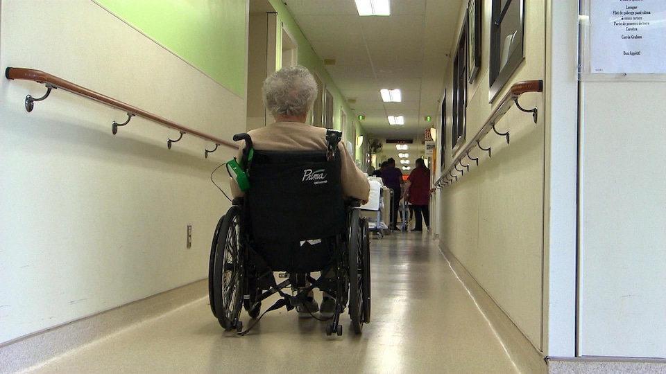 Une femme se déplace dans un couloir en fauteuil roulant.