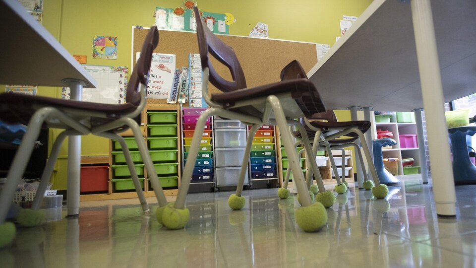 Des chaises avec des balles de tennis autour des pattes dans une classe d'école.