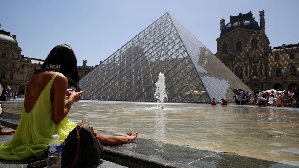 Une femme est assise près d'une fontaine à Paris. 
