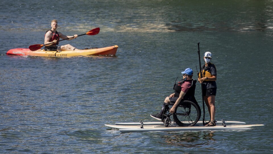 Un homme en fauteuil roulant avance sur une planche adaptée à False Creek, à Vancouver.