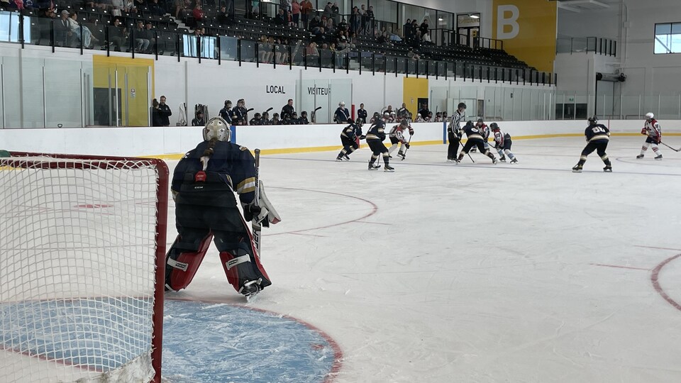 Des joueuses de hockey s'affrontent dans un aréna devant des spectateurs dans les gradins.