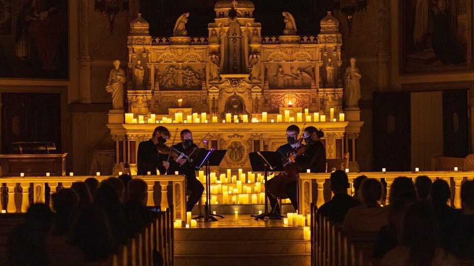 Performance d'un quatuor à cordes, éclairé par des chandelles, dans la chapelle Notre-Dame-de-Bon-Secours à Montréal.