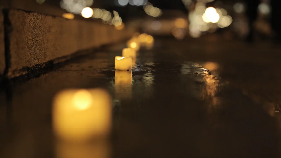 Des bougies allumées et alignées sur une marche.
