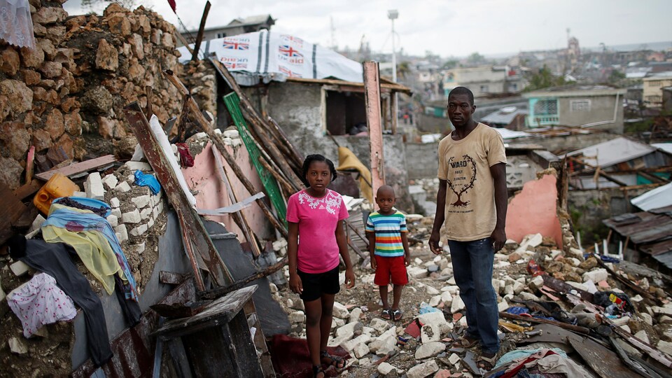 Une famille haïtienne désemparée prend la pose parmi les décombres de sa maison, après l'ouragan Matthew en 2016.