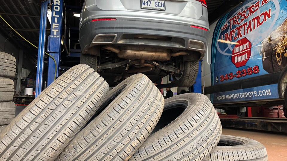 Des pneus se retrouvent devant un véhicule dans un garage.