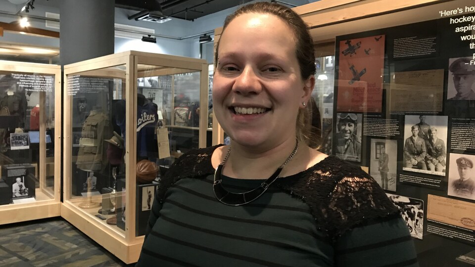 Une jeune femme avec les cheveux attachés sourit à l'objectif.