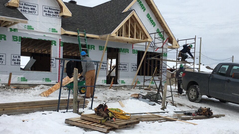 Des travailleurs construisent une maison en hiver.