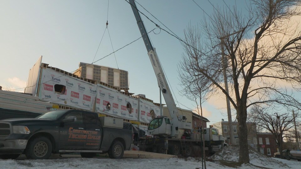 Un chantier de construction avec une camionnette à l'avant et une grue à l'arrière.