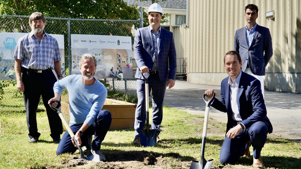 Les différentes parties prenantes au projet Lab-École se tiennent devant le chantier du futur pavillon. Certains sont munis de pelles.