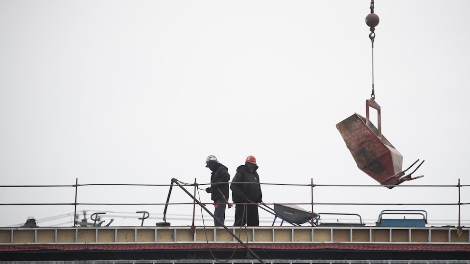 Deux ouvriers travaillent côte à côte sur un chantier.