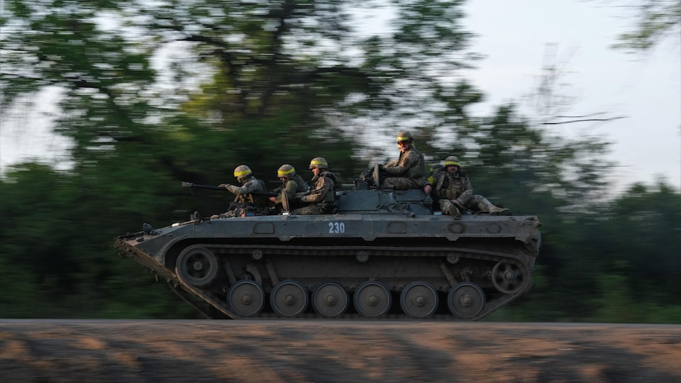 Des soldats circulent dans un char d'assaut.