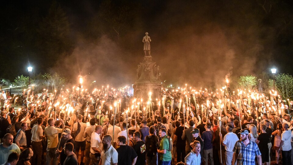 Des nationalistes blancs, essentiellement des hommes,  participent à une marche aux flambeaux devant la statue du général sudiste Robert Lee.