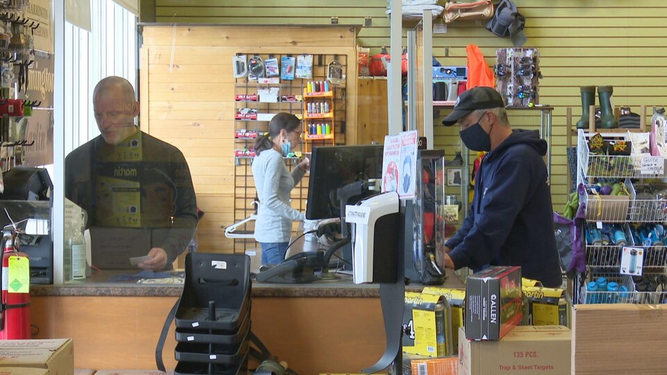 Un client fait un achat à la caisse de la boutique de chasse et pêche.