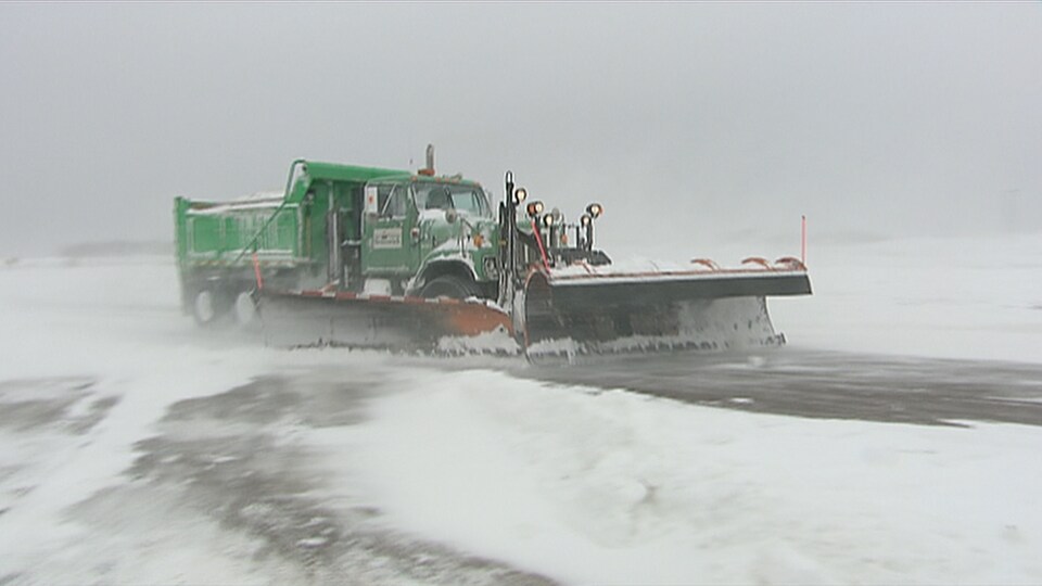 Un chasse-neige déblaie une route durant une tempête de neige